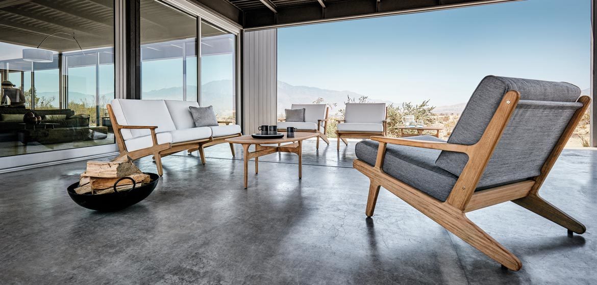 Bay teak outdoor sofa and lounge chairs by Gloster at a modern home on a stained and polished concrete patio