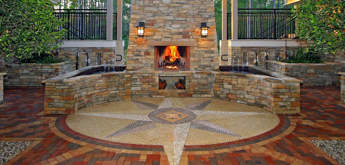 isokern outdoor fireplace with natural stone veneer exterior on brick paver patio with circular tile inlay and large star medallion