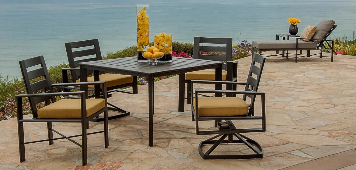 O W Lee Gios collection modern aluminum outdoor dining furniture on irregular flagstone patio by the ocean