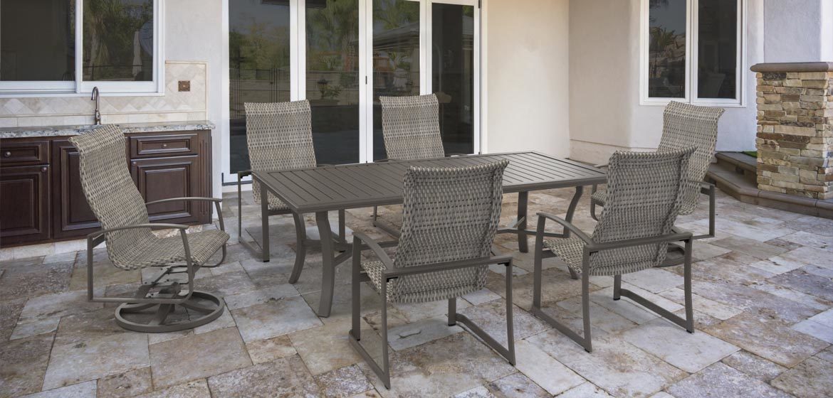 Tropitone's Mainsail Woven outdoor dining furniture on a travertine patio next to an outdoor kitchen