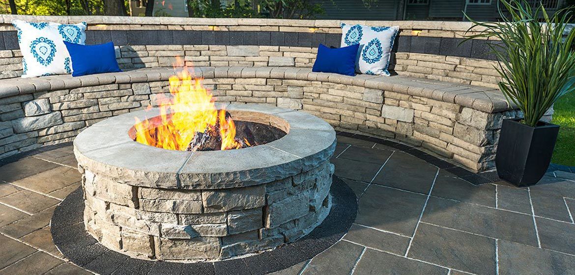 unilock rivercrest fire pit with rivercrest seating wall and colorful outdo...