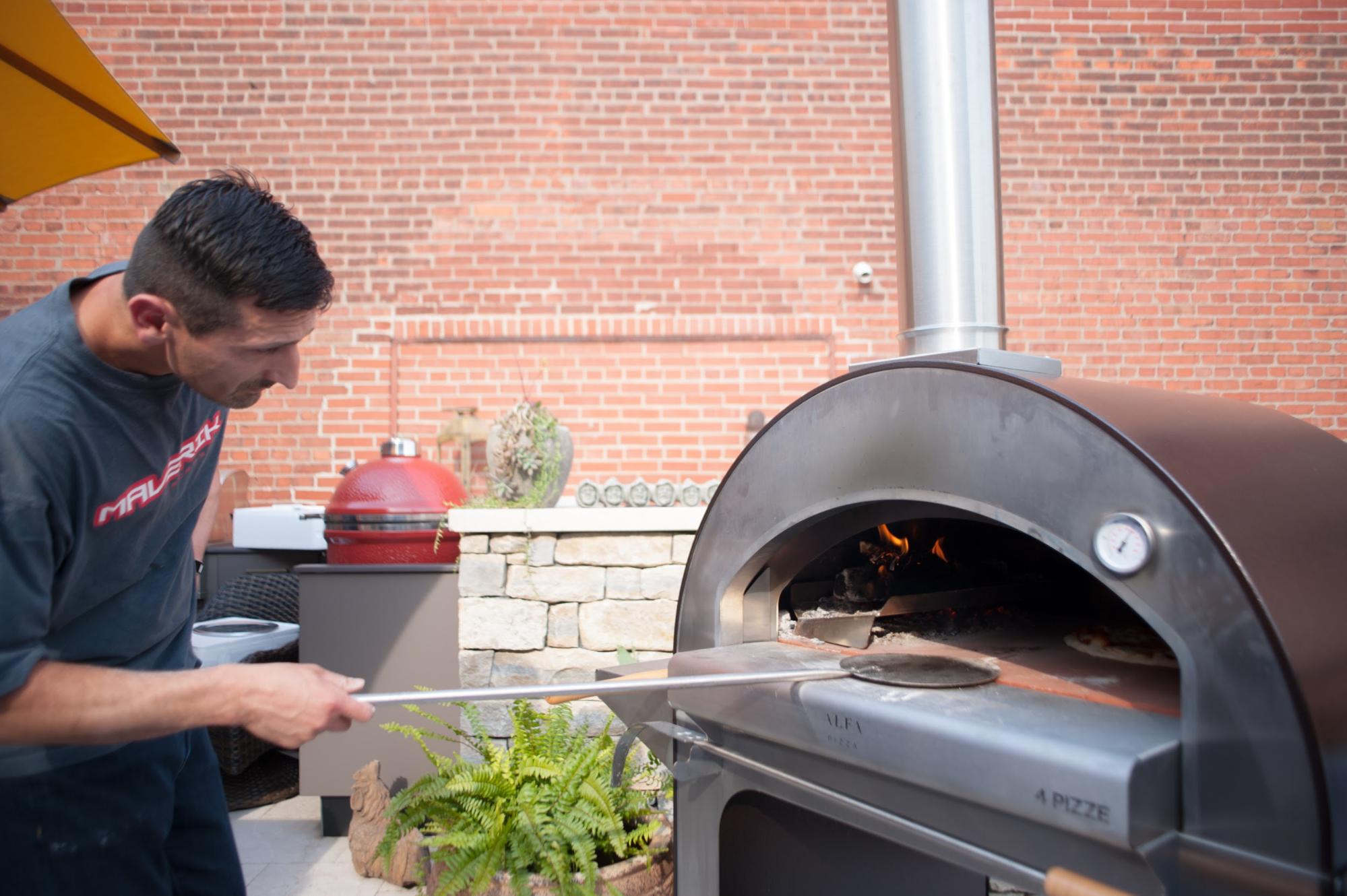 Man tending to pizza in ALFA 4 Pizze oven