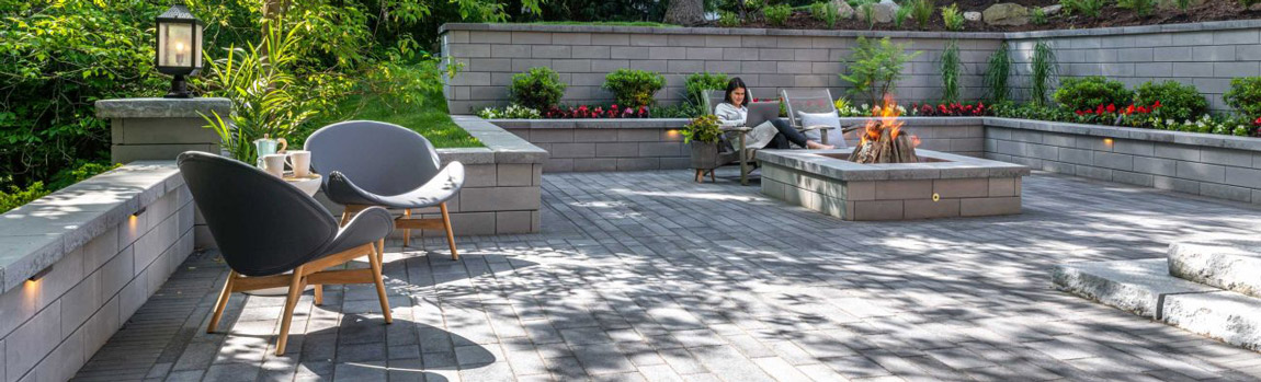 <php relax by a cozy fire pit built with unilock u-cara wall on a beautiful contemporary artline paver patio ?>